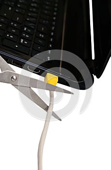 Scissors cut the cable connected to a laptop