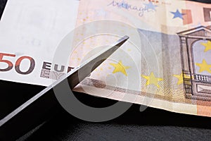 Scissors cut a euro bill close up