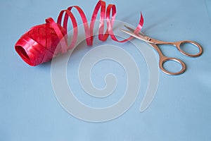 Scissors cut the red ribbon on blue background