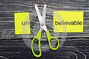 Scissors cut the word unbelievable. concept believable. cuts the word