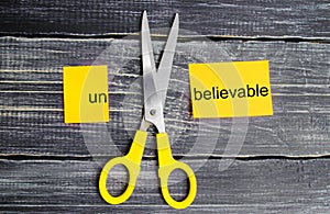 Scissors cut the word unbelievable. concept believable. cuts the word