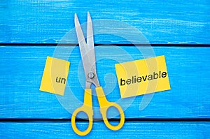 Scissors cut the word unbelievable. concept believable. cuts the word