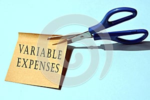 Scissors that cut yellow notepad with variable expenses text
