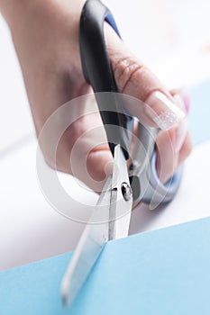 Scissors cutting a blue cardboard