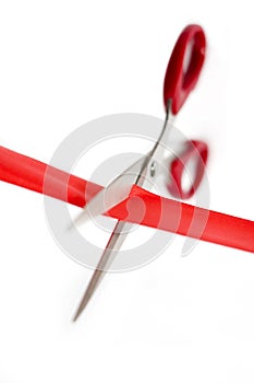 Scissors cutting through a red ribbon. Conceptual image