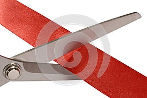 Scissors cutting red ribbon or tape, close up