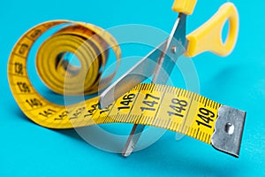 Scissors cutting yellow measuring tape dieting concept