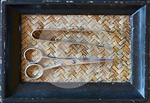 Scissors and forceps on boutique wooden basket tray in Thai or asian culture,closed up