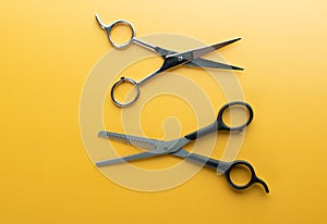Scissors for haircut and thinning hair on yellow background, open and close up
