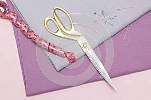 Scissors and a measuring tape lie on the caresses of the fabric. sewing hobby concept.