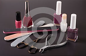Scissors, nail files and clippers manicure with polish bottles on a dark background
