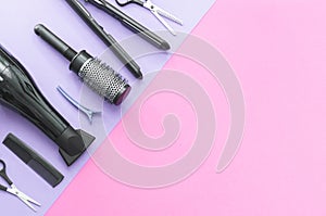 Scissors and other hairdresser's accessories on lilac-pink background, flat lay. Space for text