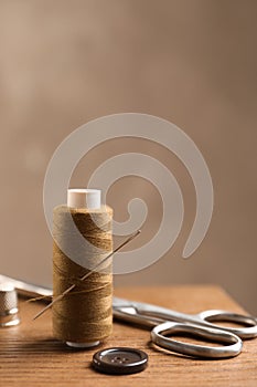 Scissors and other sewing accessories on wooden table, space