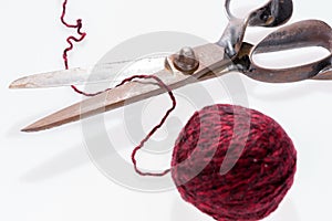 Scissors and a red ball of woolen thread isolated