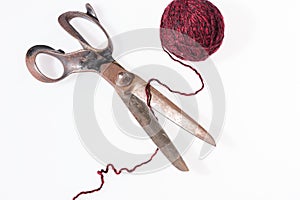 Scissors and a red ball of woolen thread isolated