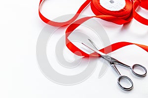 Scissors and red ribbon on a white background.