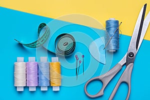 Scissors, set of sewing needles and bright colored threads on reels.