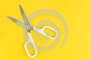 Scissors on solid yellow background with copy space using as haircut fashion or cost expense or budget cut and reduction