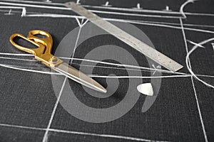 Scissors, tailor`s chalk and ruler on grey fabric with sewing patterns