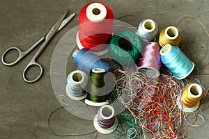 Scissors, tangled colored threads and bobbins of thread