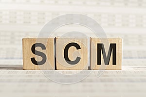 SCM abbreviation - Supply Chain Management, on wooden cubes on a light background