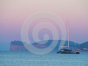 Scogliera di Capo Caccia and a yacht on a sea on Sardinia, Italy