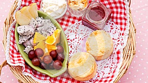 Scone, strawberry jam, almond, and mixed fruit in a basket