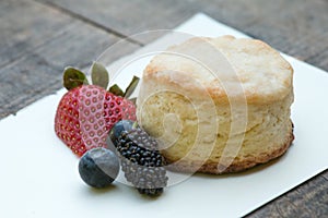 Scones with strawberries, blueberry and mulberry on wooden table