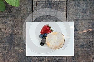 Scones with strawberries, blueberry and mulberry on wooden table