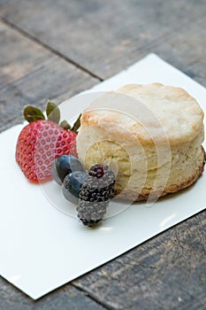 Scones with strawberries, blueberry and mulberry on wooden table