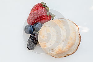 Scones with strawberries, blueberry and mulberry on wooden table