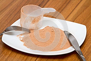 Scoop of chocolate whey protein on a plate