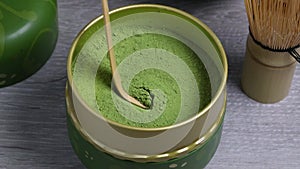 Scoop of green matcha tea with a traditional bamboo spoon