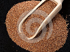 Scoop on pile of wholegrain teff seeds on black