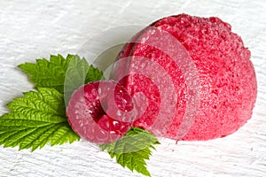 Scoop of raspberry ice cream with fresh fruit and green leaf