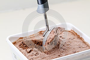 Scoop serving chocolate ice cream from a tub