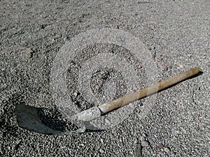 Scoop shovel casually lies on the surface of small gravel