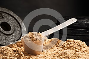 Scoop of whey protein on black background. Chocolate flawour