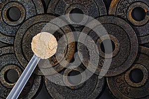 Scoop of whey protein on black background. Top view