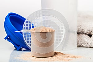 Scoop of whey protein in front of gym equipment