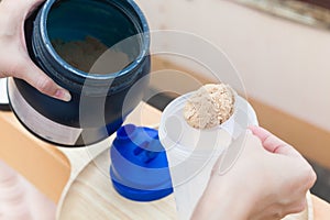 Scoop of whey protein on a wooden plate with jar.