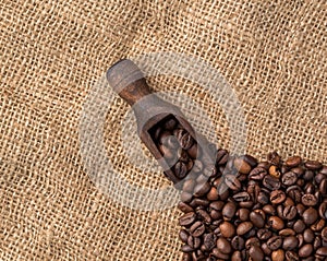 Scooper with coffee beans on jute background.