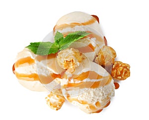 Scoops of delicious ice cream with mint, caramel sauce and popcorn on white background