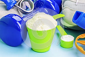 Scoops with whey protein and creatine with sport items around