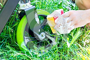 Scooter washing process. Washcloth with foam in a female hand.