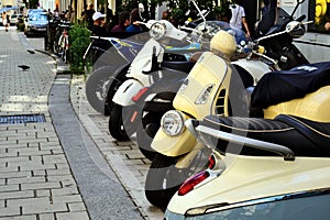 scooters and motor bikes parked in a row in busy downtown street. patio and street restaurant terrace