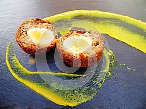 Scotch Egg halved with Yellow Mustard on Slate Plate