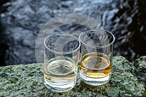 Scotch single malts or blended whisky spirits in glasses with water of river Spey on background, Scotland