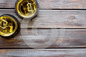 Scotch - two glasses with ice - on dark wooden background top-down frame copy space