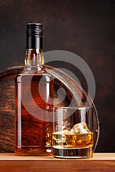 Scotch whiskey bottle, glass and old barrel